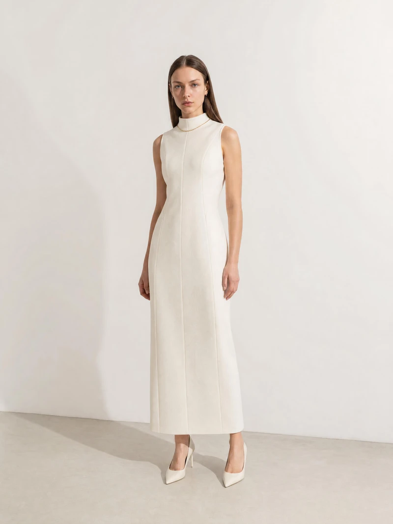 Nikita in a long ivory dress photographed in a sunlit studio
